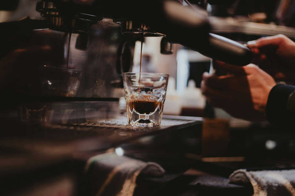 A shot of espresso being pulled on a commercial espresso machine