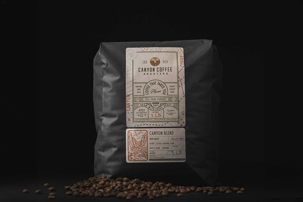 5 pound bag of Canyon Coffee Roasters coffee surrounded by roasted coffee beans